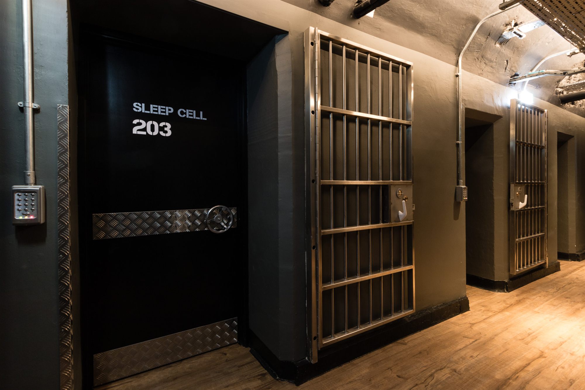 Corridor of former jail cells with original barred gates, now Sleep Cells at CODE The Court