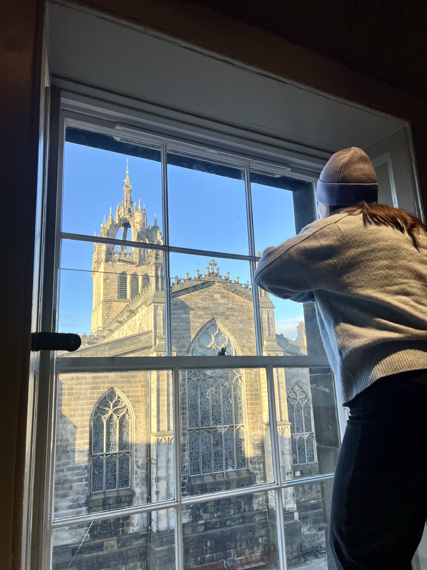 A guest looking out of a window at CODE The Court towards St Giles' Cathedral